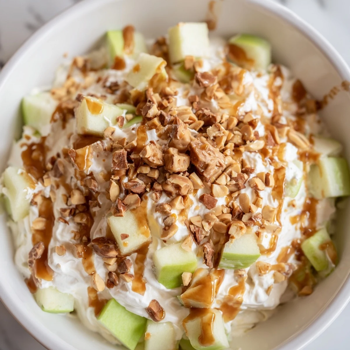 A colorful bowl of Snickers Salad with crunchy apples and creamy whipped topping.