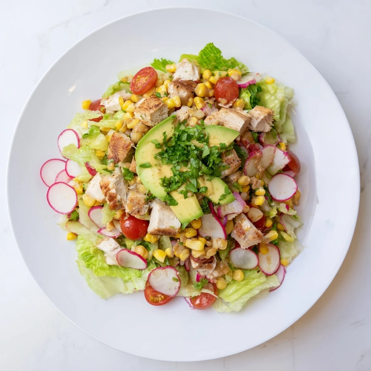 Overhead view of Roasted Corn & Chicken Chopped Salad with cherry tomatoes, radishes, and fresh cilantro garnish.