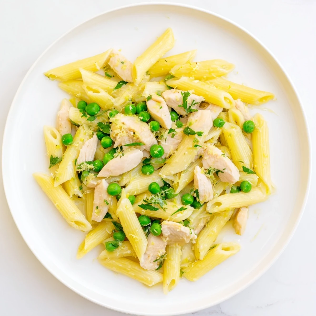 A serving of Pea & Mint Chicken Pasta with tender chicken, bright green peas, and fresh mint in a glossy lemon sauce.