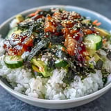 Deconstructed sushi bowl featuring crisp nori strips, julienned vegetables, and creamy spicy mayo for a vibrant meal.