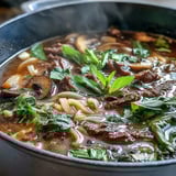 Vibrant hot pot feast featuring simmering broth, thinly sliced sirloin, crisp bok choy, and fragrant herbs, perfect for interactive dining.  