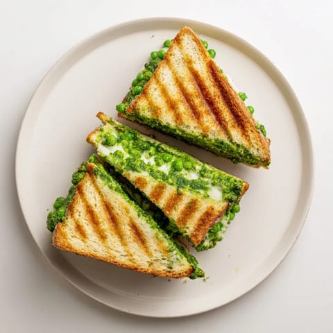 Close-up of a Spring Pea Pesto Grilled Cheese, showing bright green pesto and gooey cheese between crisp slices.