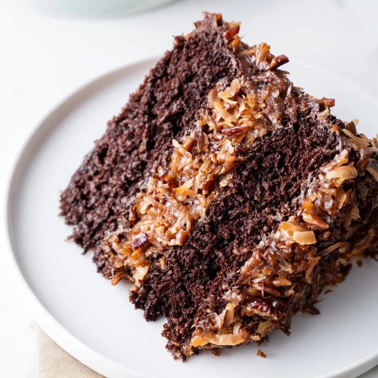 Close-up of a frosted German Chocolate Cake, highlighting the coconut-pecan topping's texture and enticing aroma.