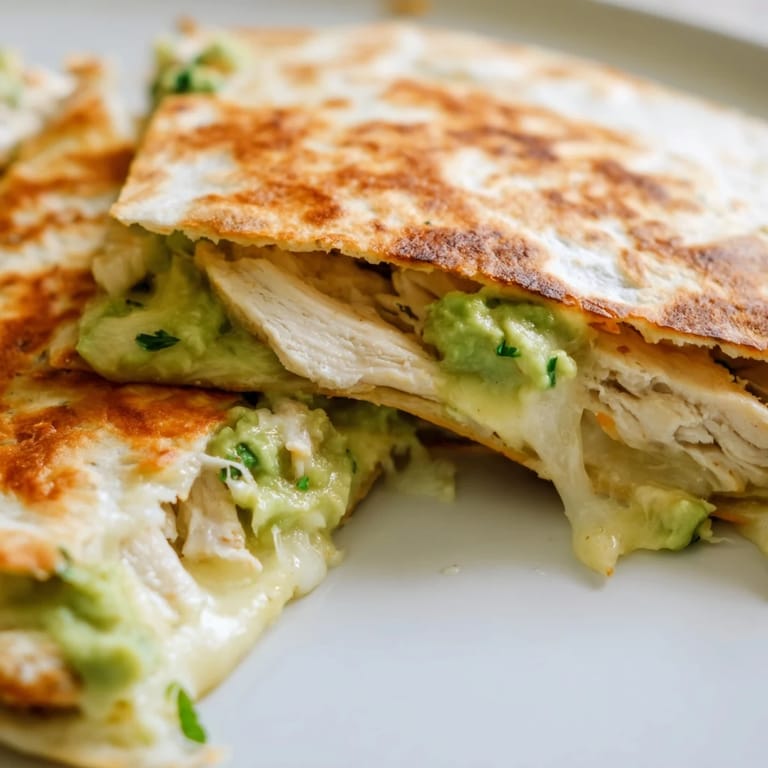 Freshly cooked Chicken Avocado Quesadilla, featuring gooey Monterey Jack cheese, juicy chicken strips, and vibrant red onion slices.