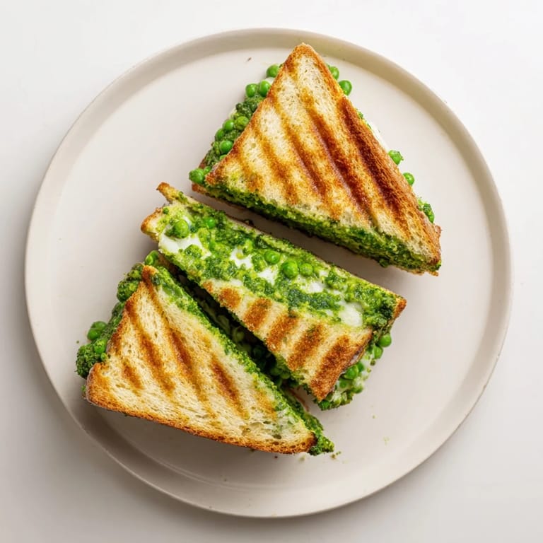 Close-up of a Spring Pea Pesto Grilled Cheese, showing bright green pesto and gooey cheese between crisp slices.