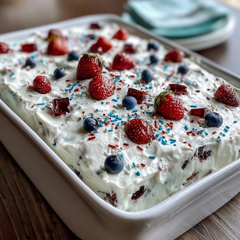 Delicious Red White Blue Poke Cake layered with vibrant gelatin and cool whipped cream.