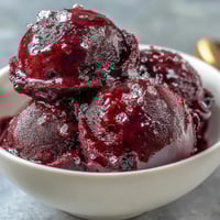 Vibrant black currant sorbet with deep purple hue and fresh mint garnish.  